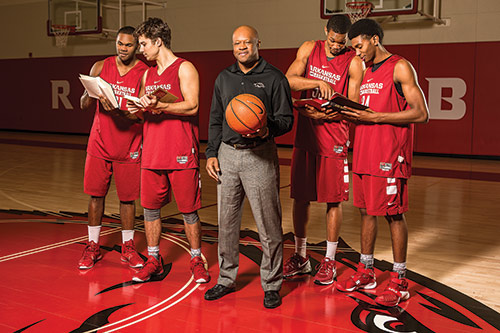 Coach Mike Anderson with Razorback basketball players holding books