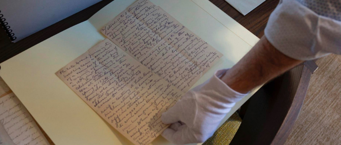 gloved hand holds handwritten page in the exhibit