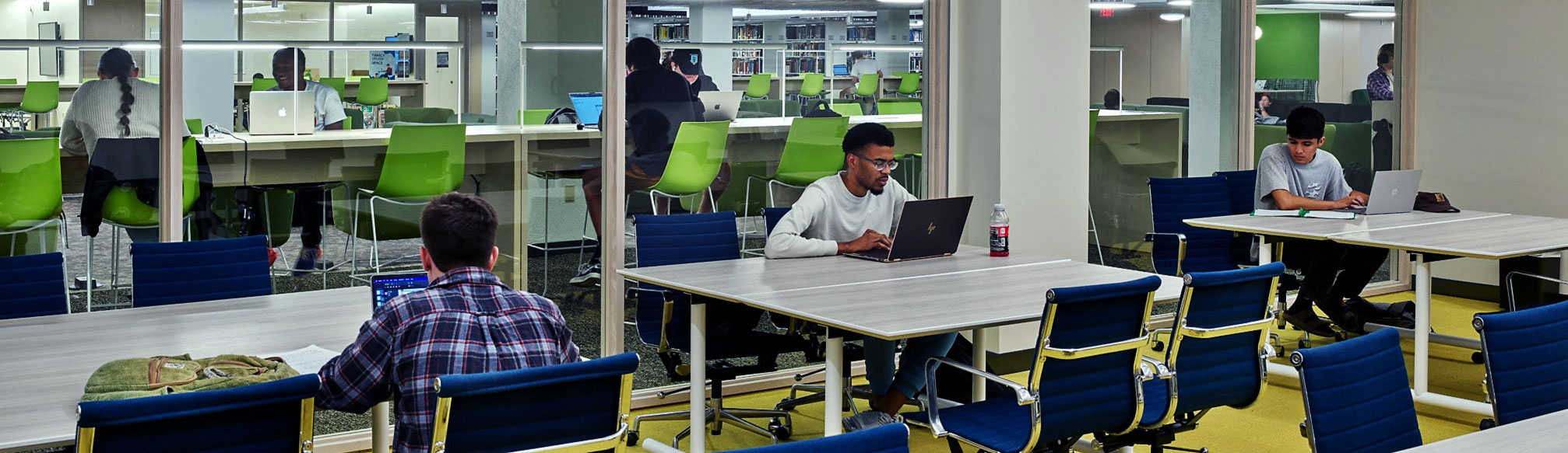multiple students sitting at tables with laptops in mullins library
