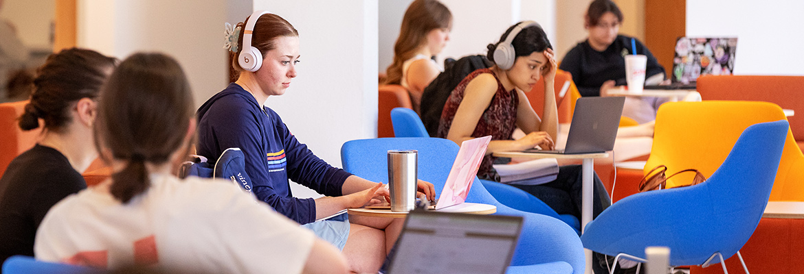 students study in Mullins Library on laptops among colorful seating